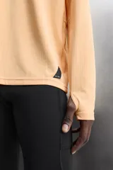 Camiseta deportiva color durazno de manga larga con orificios para los pulgares.