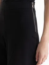 Pantalon de corte amplio y estilo culotte, confeccionado en tejido de punto color negro. Presenta cintura elastizada, cierre lateral y detalles de costuras verticales con pespuntes decorativos que recorren el frente de las piernas.