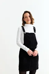 Jumper corto de pana negra con tirantes ajustables, bolsillos frontales y corte recto.