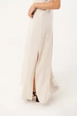 Vestido largo color beige de lino imperial, con escote en V, espalda con tirantes anchos y bordados en la parte superior. Tiene tajos a ambos lados.