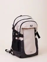 Mochila de nylon ripstop color beige y negro, con compartimento frontal con cierre y logo de Rusty. Posee correas ajustables y bolsillos laterales de malla.