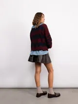 Campera de punto con cierre frontal bidireccional, mangas largas abullonadas y diseño calado con patrón de ondas en color negro con detalles brillantes.