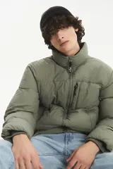 Campera puffer de corte estándar, color verde oliva, con cierre frontal completo, cuello alto y bolsillos laterales con cierre.