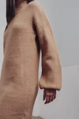 Vestido corto de punto color fucsia, con cuello alto y mangas largas amplias. Diseño holgado y cómodo.