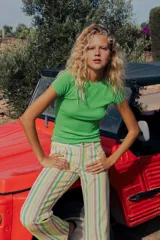 Jeans wide leg de tiro bajo con diseño de rayas verticales en tonos verde, amarillo y beige. Cuenta con cinco bolsillos, presillas para cinto y cierre frontal con cremallera y botón metálico.