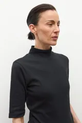 Remera de cuello alto tipo media polera, de manga corta y corte ajustado al cuerpo, en color crudo.