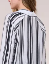Camisa de crepe blanca con rayas verticales negras, cuello camisero, mangas largas raglán y cierre frontal con botones.