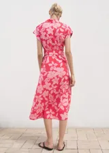 Vestido midi de viscosa color fucsia con estampado floral en tonos rosados, diseño recto, cuello camisero, manga corta, cierre frontal de botones y cinturón ajustable del mismo género.
