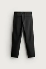Pantalón de corte slim fit y color negro, confeccionado en tejido elástico. Cuenta con cintura elástica, trabillas, bolsillos frontales y cierre con cremallera y botón.