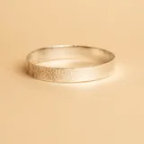 Brazalete tipo esclava rígida de plata 925 con acabado martillado y textura irregular.