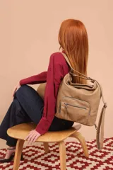 Cartera mochila color tostado, de cuero sintético, con compartimento principal amplio y bolsillos frontales con cierre. Tiene correas ajustables y asa superior para llevar al hombro o como mochila.