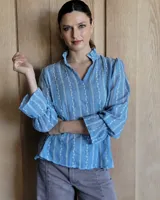 Blusa de algodón con cuello mao y volados, mangas largas con puños elásticos y corte holgado.