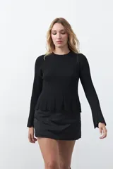 Top de tejido acanalado con sutil acabado metalizado, de silueta entallada con diseño peplum en la cintura y mangas largas levemente acampanadas.