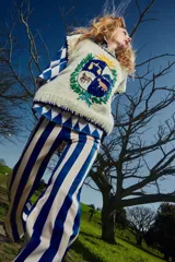 Chaleco de lana merino color crema, tejido y bordado a mano, con diseño de escudo con animales y sol.