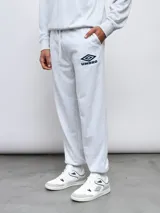 Pantalón jogger de felpa sin frisa, color gris claro melange, con logo bordado de Umbro en azul oscuro en el muslo izquierdo y puños elásticos en los tobillos.