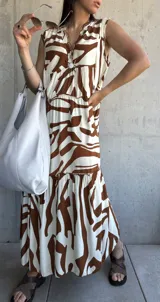 Vestido largo color blanco con estampado abstracto en marrón, con escote en V y corte escalonado.