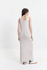 Vestido largo de punto con textura acanalada, escote redondo y tirantes anchos. Presenta una silueta ajustada al cuerpo y un tajo lateral en la parte inferior.