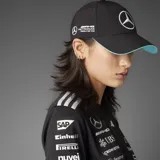 Gorra Adidas de la colección Mercedes, color negro con el logotipo de Mercedes-Benz bordado en blanco en el panel frontal y el emblema de Adidas en el borde de la visera, la cual cuenta con un ribete en tono verde agua.