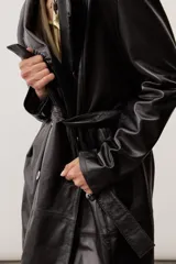 Chaqueta negra de cuero con cuello camisero, mangas largas y costuras decorativas.