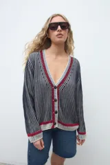 Cardigan de punto azul con diseño de rayas verticales, cuello en V con ribetes en rojo, blanco y azul, mangas largas y cierre frontal con botones.