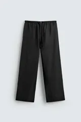 Pantalón de corte relajado confeccionado en tejido fluido con mezcla de lyocell. Presenta cintura elástica ajustable con cordón, bolsillos laterales y un bolsillo trasero de vivo con botón.