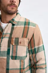Sobrecamisa de franela con estampado de cuadros en tonos marrones y verdes, cuenta con cierre frontal, cuello clásico y bolsillos con solapa en el pecho.