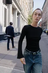 Camiseta de cuello redondo y manga larga con terminación acampanada en los puños, de corte ajustado al cuerpo.