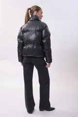 Campera puffer de efecto cuero negro, con cuello alto, cierre frontal y diseño acolchado.