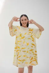Vestido corto acampanado color crema con estampado de hojas amarillas, cuello redondo y mangas cortas.