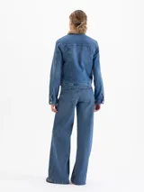 Campera de jean tipo trucker con interior de corderito sintético, cierre frontal con botones metálicos y bolsillos en el pecho.