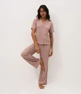 Pijama largo de dos piezas confeccionado en ribana con estampado de cuadros vichy en tonos marrón y blanco. Incluye una blusa de manga corta con cuello solapa, cierre frontal de botones y detalles de vivo contrastante, y un pantalón de pierna recta con cintura elástica.