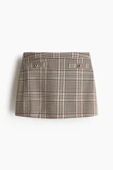 Short pollera de tiro alto con estampado a cuadros, falsos bolsillos delanteros con botones dorados y cierre oculto en el lateral.