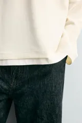 Camiseta de manga larga con corte relajado y cuello redondo. Presenta un diseño de doble capa con acabados en rib a contraste en el cuello y el ruedo.