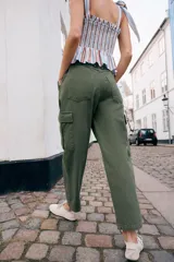 Pantalón cargo de tiro medio con pinzas delanteras, bolsillos laterales de plastrón y cierre frontal con cremallera y botón. Presenta una pernera holgada que se estrecha ligeramente hacia el bajo.