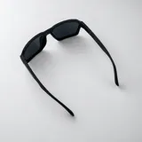 Lentes de sol polarizados con armazón negro de diseño geométrico y detalles metálicos en las patillas.