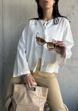 Chaqueta blanca de algodón con bordados florales en puños y ruedo, escote con lazos y mangas largas acampanadas.