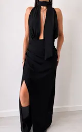 Vestido largo negro de fiesta, con escote halter pronunciado, detalle de cuello tipo choker con tiras colgantes y falda larga con abertura lateral.