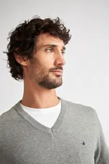 Sweater de tejido de punto con escote en V y manga larga. Presenta un diseño de calce regular con puños y ruedo acanalados, e incluye un pequeño logo bordado en el pecho.