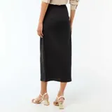 Falda larga de color negro con diseño cruzado y detalle de hebilla metálica dorada en la cintura. Presenta un corte midi con caída fluida y una abertura frontal.