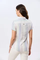 Camisa de lino de manga corta con rayas en tonos suaves, cuello camisero, cierre frontal parcial con botones y un bolsillo en el pecho.
