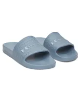 Ojotas Under Armour modelo W Armr Slide Lite de color gris, confeccionadas en EVA moldeada de una sola pieza. Presenta una tira ancha con textura geométrica y el logo de la marca en relieve.