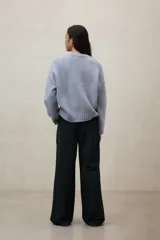 Suéter de punto color beige claro jaspeado, de corte holgado y cuello redondo. Presenta un tejido de punto acanalado en el cuello, puños y bajo.