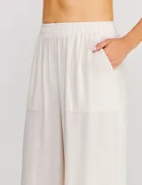 Pantalón palazzo de tiro alto color beige, confeccionado en mezcla de lino y viscosa, con silueta suelta y fluida, cintura elastizada, bolsillos delanteros aplicados y ruedo festoneado de corte tobillero.