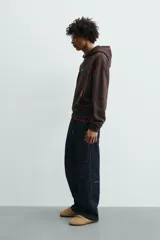 Sudadera con capucha de corte relajado, color marrón oscuro, con interior perchado. Presenta un bolsillo frontal tipo canguro, bordado con la palabra 'LOVE' en el pecho y un parche decorativo a contraste en el bolsillo. Posee puños y ruedo en rib.
