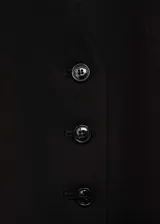 Chaleco de estilo sastre en color negro, con cuello en pico, cierre frontal de botones y dos bolsillos de ribete delanteros. Presenta un diseño recto y forro interior.