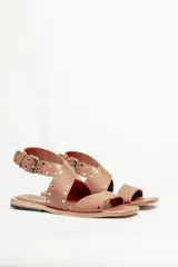 Sandalias bajas de cuero negro con tachas plateadas, tiras cruzadas y hebilla al tobillo.