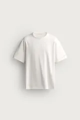 Camiseta relaxed fit color blanco, de cuello redondo y manga corta. Presenta un pequeño parche aplicado a contraste en el extremo de la manga y terminaciones en rib.