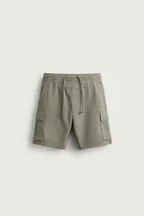 Bermuda cargo color verde militar de corte relaxed fit, confeccionada en tejido de algodón con elasticidad y efecto lavado. Cuenta con cintura elástica ajustable con cordón, bolsillos frontales, bolsillos traseros de vivo y bolsillos laterales tipo cargo con solapa en las perneras.