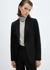 Blazer entallado de color negro con solapas de muesca, hombros estructurados y cierre frontal de un botón. Presenta bolsillos de ribete delanteros, abertura posterior y forro interior.