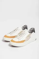 Championes Urban Haus modelo Lyon, de cuero blanco con detalles en color caramelo y beige. Presentan una suela gruesa blanca y logo de la marca en el lateral.